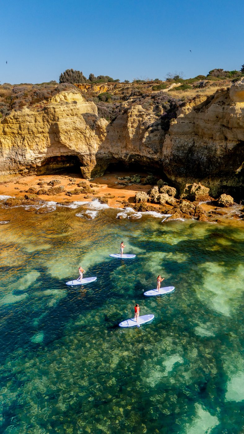 Three paddlers near Algarve cliff