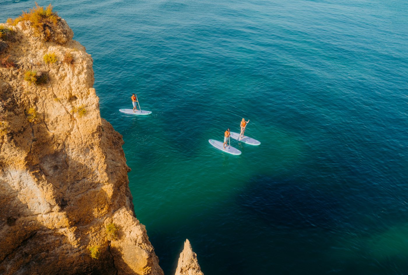 Aerial view of paddlers beside a golden Algarve cliff